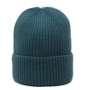 Close-up of dark green ribbed knit beanie showing thick texture and folded cuff detail