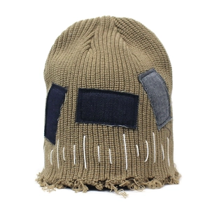 Dettaglio del berretto in maglia con toppe in denim e cuciture a contrasto bianche