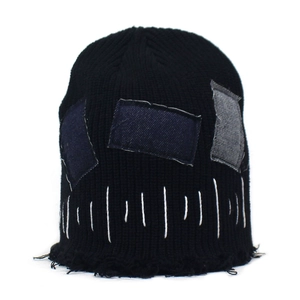 Dettaglio del berretto con toppe in denim e bordi sfrangiati su maglia nera vintage
