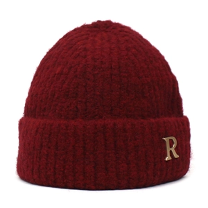 Detailed texture of burgundy knit beanie with a metallic golden R letter emblem