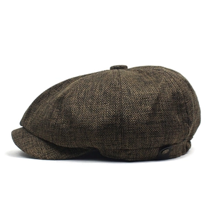 Close-up of brown textured octagonal newsboy cap with classic leather side button detail