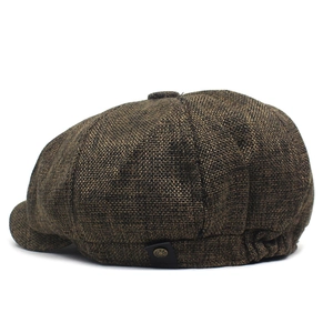 Detail of vintage linen-style newsboy cap fabric texture and decorative leather button