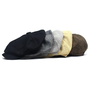 Close-up of linen-textured newsboy caps in black, grey, beige and brown tones
