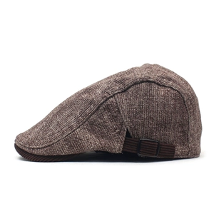 Detail view of brown tweed flat cap with corduroy adjustable side strap and metal buckle