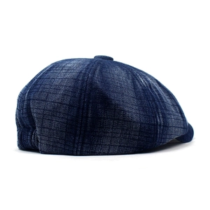 Detail of blue denim newsboy cap with dark plaid texture and vintage button top