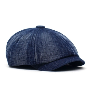 Detailed close-up of dark blue washed denim fabric and texture on a newsboy cap