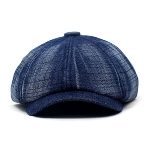 Detailed view of dark blue denim newsboy hat with subtle plaid pattern and textured stitching