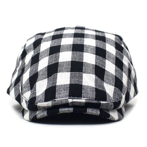 Detailed close-up showing the fine black and white plaid pattern on the classic flat cap