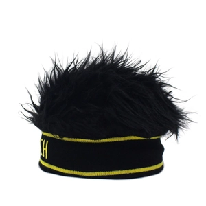 Detail van de gebreide muts met zwart afrohaar en geel geborduurd streepontwerp