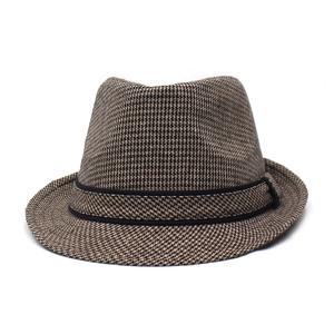 Detail of a brown and black houndstooth fedora hat with a black decorative ribbon
