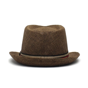 Détail d'un chapeau de paille marron foncé avec ruban rayé rouge et noir pour l'été