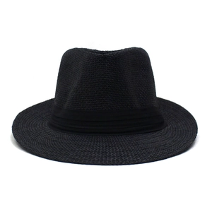 Gros plan d'un chapeau fedora en paille noire avec texture tressée et ruban élégant
