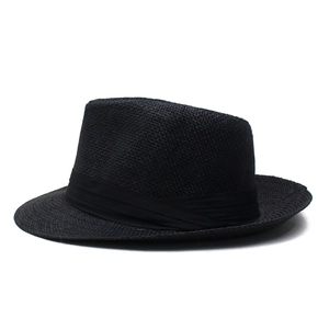Gros plan d'un chapeau Fedora noir en paille tissée avec ruban en satin et texture fine