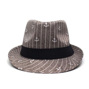 Détail d'un chapeau fedora marron avec motifs d'ancres blanches et ruban noir décoratif