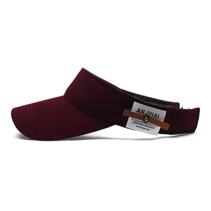 Detail view of burgundy cotton sun visor featuring white label and leather strap buckle