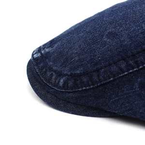 Détail du tissu denim délavé avec double surpiqûre sur un béret bleu marine