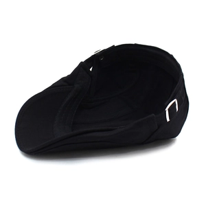 Détail d'une casquette plate en coton noir avec boucle de réglage en métal argenté sur blanc