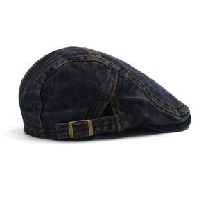 Detail of washed denim beret featuring yellow contrast stitching and adjustable bronze buckle
