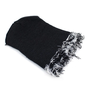 Detail showing the distressed knit texture and black and white fringe on the beanie