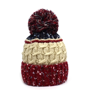 Détail du bonnet d'hiver tricoté multicolore avec gros pompon et texture en maille torsadée