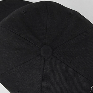 Top view detail of a black cotton six-panel baseball cap showing stitching and button