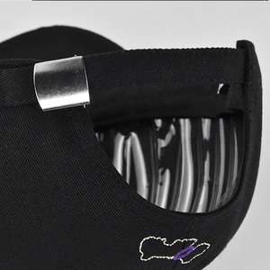 Detail of adjustable metal buckle and embroidery on a black cotton baseball cap