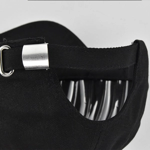 Detalle de la hebilla metálica plateada y correa ajustable trasera de la gorra de béisbol negra