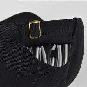 Dettaglio del cappellino nero con fibbia in metallo bronzo e cinturino regolabile