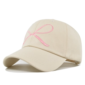 Casquette de baseball beige avec nœud rose brodé et visière courbée sur fond blanc