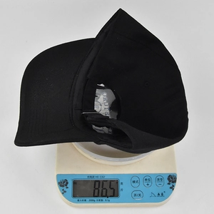 Detailed view of black cotton baseball cap on electronic scale showing weight of 86.5g