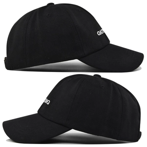 Close-up of white letter embroidery detail on black cotton twill baseball cap side