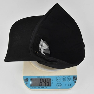 Détail d'une casquette de baseball noire brodée sur une balance pesant 84,9 grammes