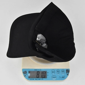 Detail view of a black embroidered baseball cap on a digital scale weighing 81.0 grams