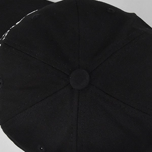 Top view detail of a black cotton twill baseball cap showing crown button and stitching