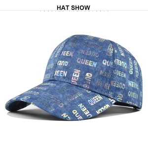 Detail of blue denim baseball cap featuring colorful holographic QUEEN print on texture