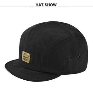Dettaglio del cappello hip-hop nero a 5 pannelli con etichetta tessuta gialla e occhielli