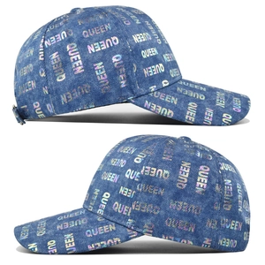 Macro detail of washed denim baseball cap featuring holographic QUEEN letter printing