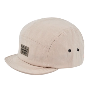 Dettaglio del cappellino camp beige a 5 pannelli con etichetta tessuta e occhielli neri