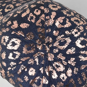 Macro shot of navy blue denim baseball cap with rose gold metallic leopard print texture