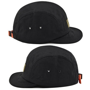 Dettaglio del cappello camper nero a cinque pannelli con etichetta gialla e cinturino arancione