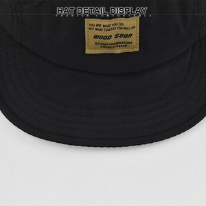 Dettaglio del cappellino nero con cuciture a vista e toppa in tessuto vintage