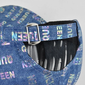Close-up of holographic QUEEN print on denim cap with adjustable silver metal buckle