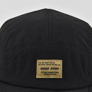 Dettaglio del cappello camper a 5 pannelli in nylon nero testurizzato con etichetta tessuta