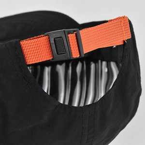 Dettaglio del cinturino regolabile in nylon arancione e fibbia su un cappello hip-hop