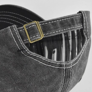 Dettaglio del cappellino in cotone lavato con fibbia in bronzo e cuciture a contrasto