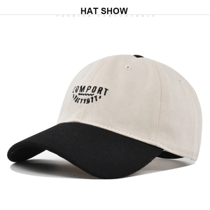 Detailed view of the black embroidered letters COMFORT PACT1977 on a beige cotton cap