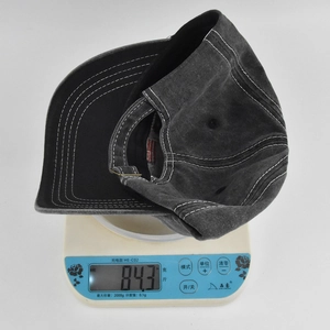 Vista dettagliata di un cappello vintage grigio lavato su una bilancia che pesa 84,3g