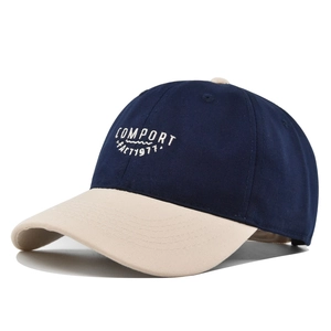 Detailed close-up of white 1977 embroidery on navy blue and beige cotton baseball cap