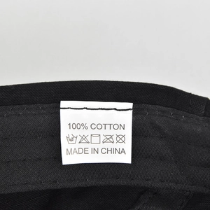 Detail of internal wash label showing 100% cotton fabric and care symbols on a black hat