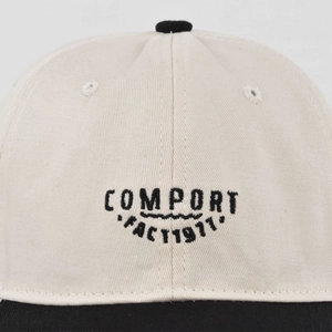 Macro detail of COMPORT embroidery and twill cotton texture on a two-tone baseball cap